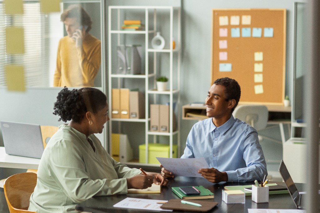 Two colleagues talking at a desk in an office